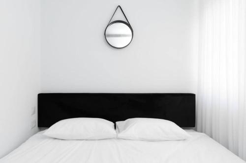 エイラットにあるאשראם 4 -דירת נופש עם חדר שינה וסלון במיקום מעולהの白いベッド(黒いヘッドボードとランプ付)