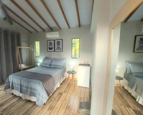 a bedroom with a large bed and wooden floors at Suíte Ilhinha II em condomínio na Praia do Perequê in Ilhabela