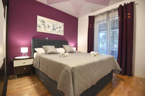 - une chambre avec un grand lit aux murs violets dans l'établissement Villa Tinov Dvor, à Briševo