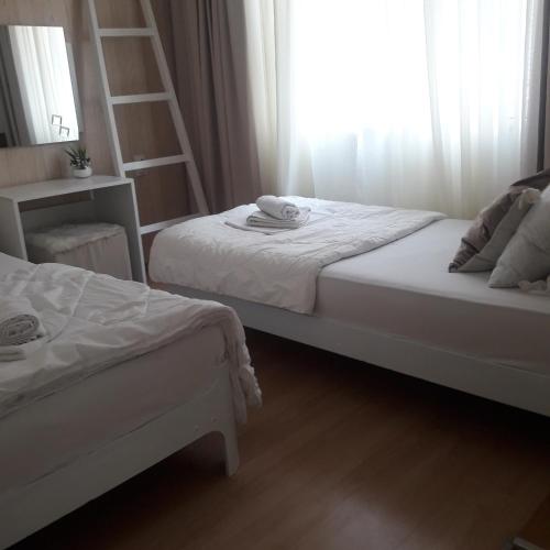 dwa łóżka w pokoju z oknem w obiekcie Apartmani Nis w Niszu