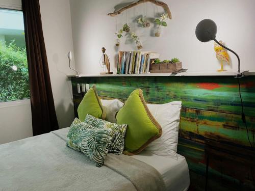 a bed with green pillows and a wooden headboard at Ojochal Gardens in Ojochal