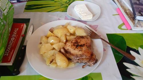 a plate of food with chicken and potatoes on a table at Ionian residence in Argostoli