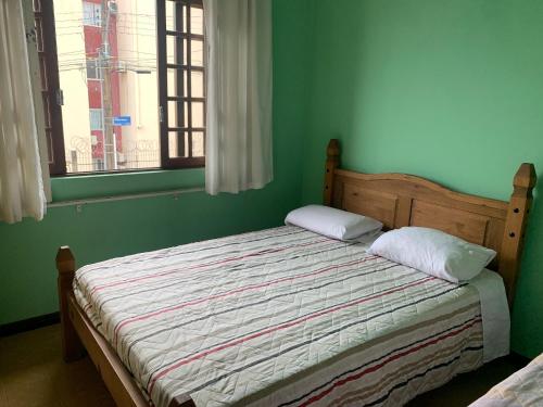 a bed in a green bedroom with a window at Ap Família no Estreito in Florianópolis