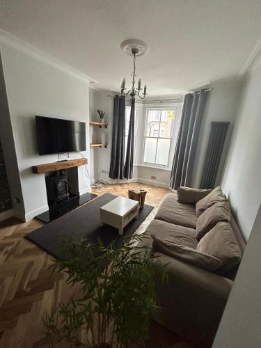 ein Wohnzimmer mit einem Sofa und einem TV in der Unterkunft Contemporary 3 bed house with spacious garden close to Stratford & Canary Wharf in London