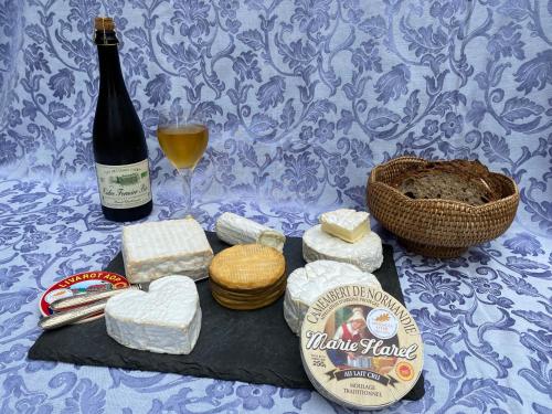 a table with cheese and a bottle of wine at Chambres et Table d'Hôtes du Coquerel in Saint-Siméon