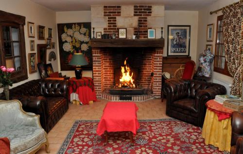 a living room with leather couches and a fireplace at Chambres et Table d'Hôtes du Coquerel in Saint-Siméon