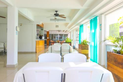 a dining room with white tables and white chairs at Terracaribe Hotel Boutique in Cancún