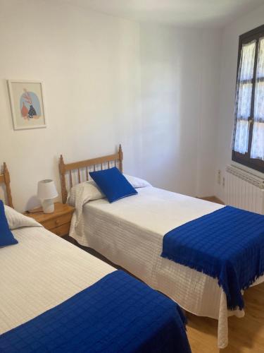 a bedroom with two beds with blue and white sheets at Casa Baratech 2C in Biescas