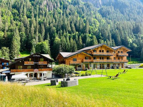 a large wooden building in front of a mountain at Hameau des Prodains - Hôtel in Morzine