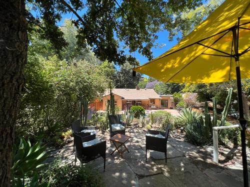 a patio with chairs and a yellow umbrella at Villa La Reforma - Newly Designed 4BR HOUSE & POOL in Los Angeles by Topanga in Los Angeles