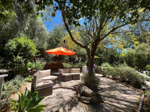 a patio with a couch and an umbrella and a tree at Villa La Reforma - Newly Designed 4BR HOUSE & POOL in Los Angeles by Topanga in Los Angeles