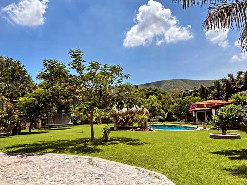 een groene tuin met een zwembad en een huis bij Casa Ticumán, villa campestre cerca de Las Estacas in Ticumán