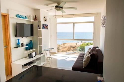 een woonkamer met een bank en een groot raam bij Dpto frente al mar, piscina, check in automático in Playas