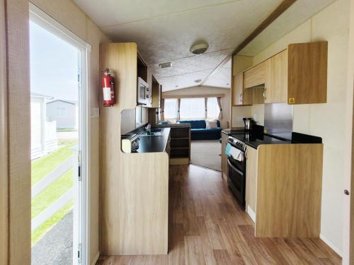eine Küche mit Holzschränken und einem großen Fenster in der Unterkunft The Burrow - 152 Mallard Lake in South Cerney