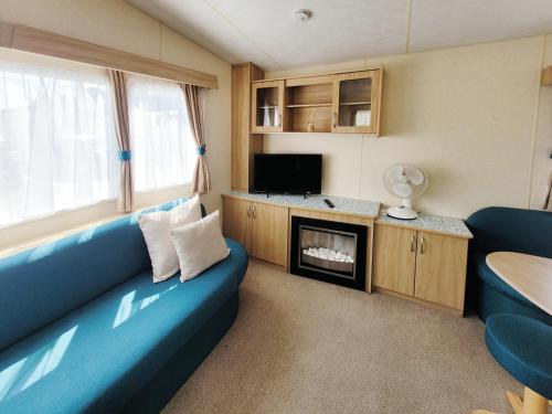 ein Wohnzimmer mit einem blauen Sofa und einem Kamin in der Unterkunft The Burrow - 152 Mallard Lake in South Cerney