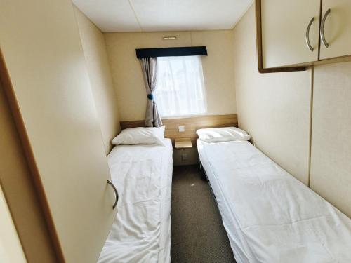 ein kleines Zimmer mit 2 Betten und einem Fenster in der Unterkunft The Burrow - 152 Mallard Lake in South Cerney