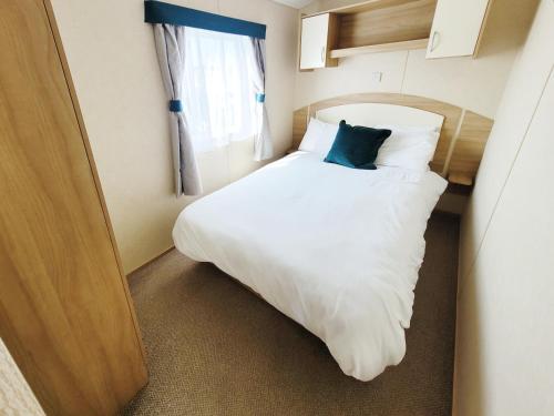 a small bedroom with a white bed and a window at The Burrow - 152 Mallard Lake in South Cerney