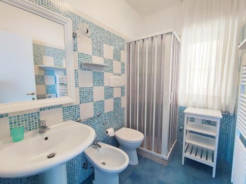 baño azul y blanco con lavabo y aseo en Ville Agnuli Case Vacanza, en Mattinata