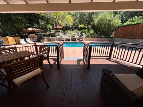 a deck with a table and chairs and a swimming pool at Villa La Reforma - Newly Designed 4BR HOUSE & POOL in Los Angeles by Topanga in Los Angeles