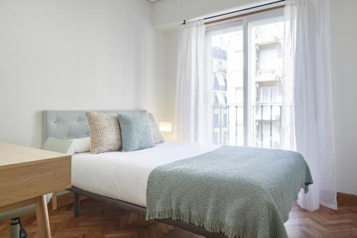 een witte slaapkamer met een bed en een raam bij Always Easy I Cristina Enea in San Sebastian