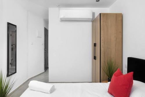 1 dormitorio con cama blanca y almohadas rojas en By Eezy - דירת סטודיו מסוגננת במיקום מעולה באילת Ashram 5, en Eilat