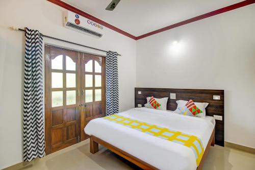 a bedroom with a bed and a wooden door at Super OYO Pradeep Guest House Near Baga Beach in Baga