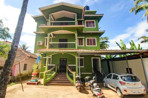 a green house with a car parked in front of it at Super OYO Pradeep Guest House Near Baga Beach in Baga