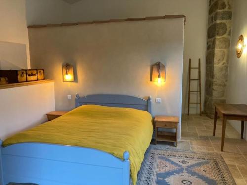 une chambre avec un lit avec une couverture jaune dessus dans l'établissement les tourettes, à Désaignes