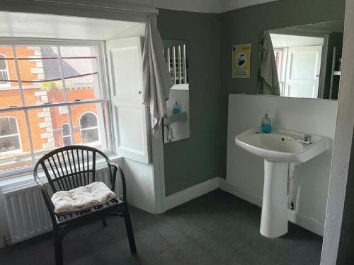 a bathroom with a sink and a chair and a mirror at Kilkenny Tourist Hostel in Kilkenny