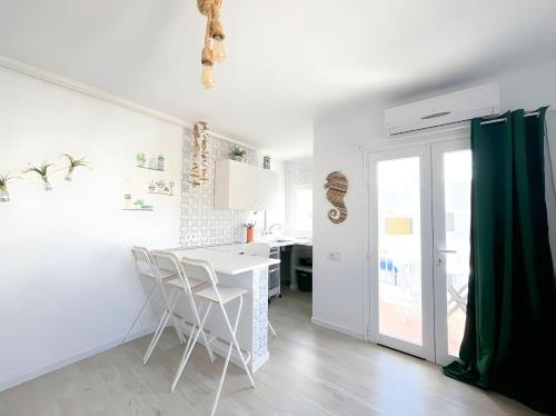 cocina blanca con mesa blanca y sillas en Apartamentos Formentera Copacabana 18, en Es Pujols