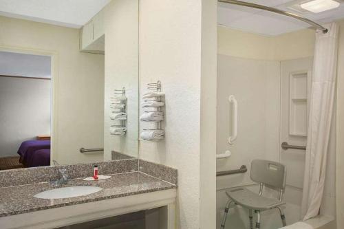 a bathroom with a sink and a shower and a chair at Economy Hotel Wichita 2 in Wichita