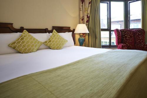 a bedroom with a white bed with pillows and a window at The Bull in Gerrards Cross