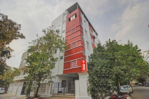 un edificio rojo y blanco con árboles delante de él en Hotel O Sri Residency Near Hyderabad Central, en Hyderabad