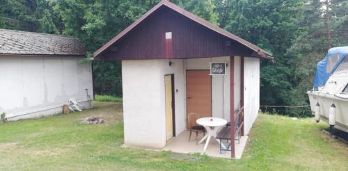 una pequeña casa con una mesa y sillas en un patio en Kemp a Loděnice Podolsko - Chatka pro 2 osoby, 