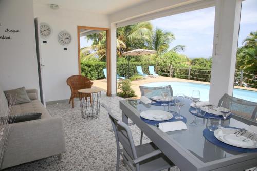 a dining room with a table and chairs and a pool at L Orchidée Bleue, bas de villa, vue mer, piscine privée in Sainte-Anne
