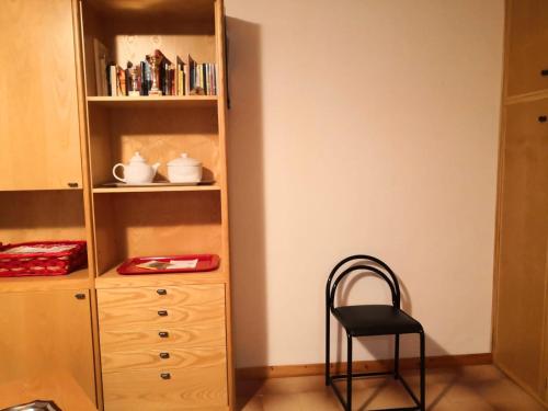 a chair sitting next to a wooden book shelf at La casa di Silvano in Cerreto Laghi