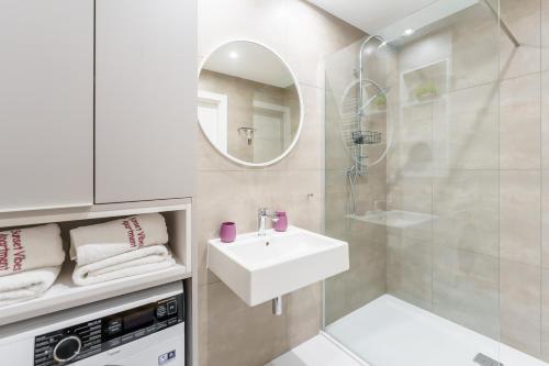 a white bathroom with a sink and a mirror at Sunset Vibes Apartment in Kołobrzeg