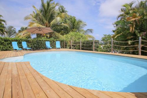 una gran piscina con sillas azules y sombrilla en L Orchidée Bleue, bas de villa, vue mer, piscine privée en Sainte-Anne