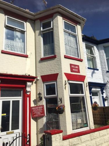 a white and red house with a red door at Holland House in Great Yarmouth