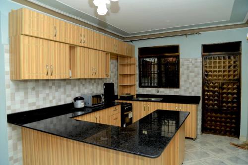 a kitchen with wooden cabinets and a black counter top at Exciting Lovely 2- bedroom unit in Kampala