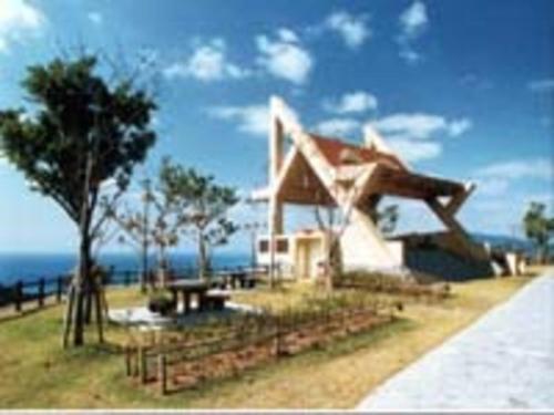 ein weißes Haus mit einem Baum und dem Meer in der Unterkunft Hotel Yamadaso - Vacation STAY 10177v in Nago