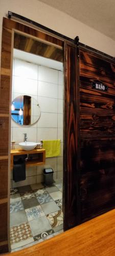 a bathroom with a sink and a wooden door at Solaire Apart in Ciudad Lujan de Cuyo
