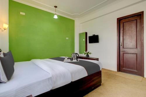 a bedroom with a large bed and a green wall at Capital O Yasmin Resort in Baghwānpur