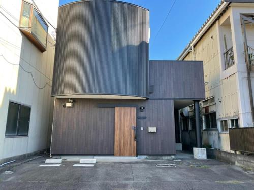 a building with a wooden door in a parking lot at Guest House Numazu Port - Vacation STAY 70099v in Numazu