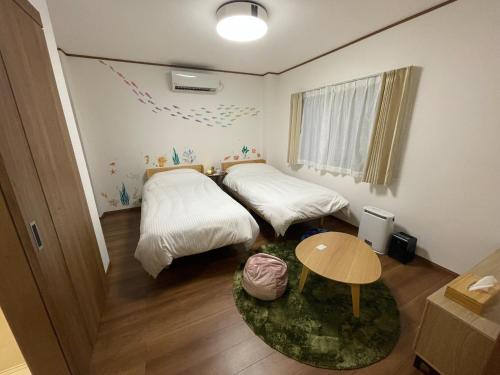 沼津市にあるGuest House Numazu Port - Vacation STAY 70099vのベッド2台とテーブルが備わる小さな客室です。