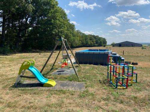 a playground with colorful playground equipment in a field at L Orée Du Bois in Moncheux