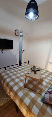 a room with a bed and a table and a clock at chambre proche de stade de france in Pierrefitte-sur-Seine