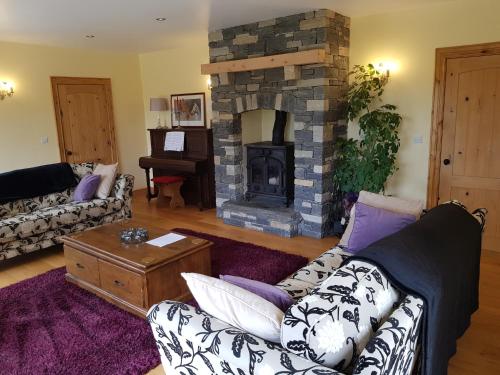 a living room with a couch and a stone fireplace at Atlantic Coast Holiday Home in Mountcharles