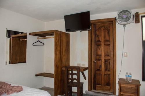 1 dormitorio con 1 cama y TV en la pared en Hotel Real del Carmen - Ideal para familias y parejas, en San Cristóbal de Las Casas