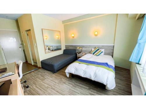 Hotel AreaOne Sakaiminato Marina - Vacation STAY 81682v في ساكايميناتو: غرفه فندقيه بسرير واريكه